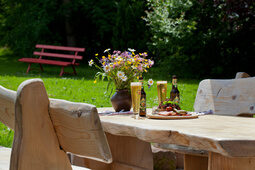 Ein hölzerner Tisch mit Getränken und Essen im Garten des Hotel Konradshof.