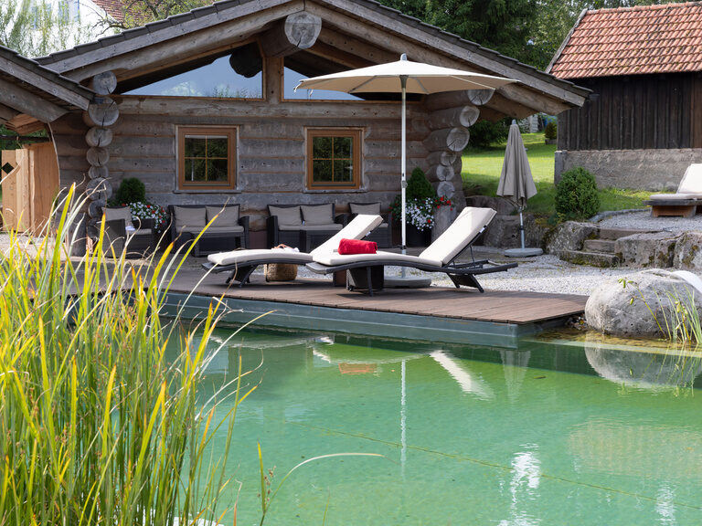 Naturschwimmteich mit Blockhaushütten vom Hotel Konradshof Besenfeld