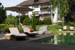 Ansicht aus dem Garten mit Liegewiese und Naturschimmteich zum Hotel Konradshof in Besenfeld
