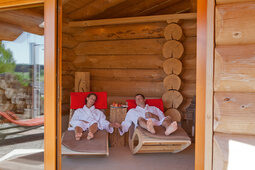 Händchen haltendes Wellness-Paar entspannt auf einer Holzliege und im Hotel Konradshof im Nordschwarzwald