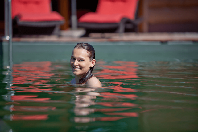 Frau schwimmt in Naturschwimmteich - Hotel Konradshof