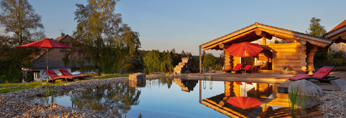Naturschwimmteich mit Blockhaushütte im Sonnenuntergang - Hotel Konradshof